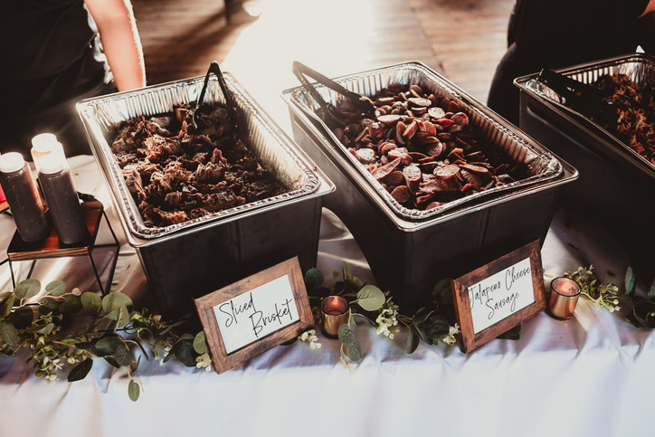 Buffet with smoked brisket and sliced jalapeño sausage at wedding reception